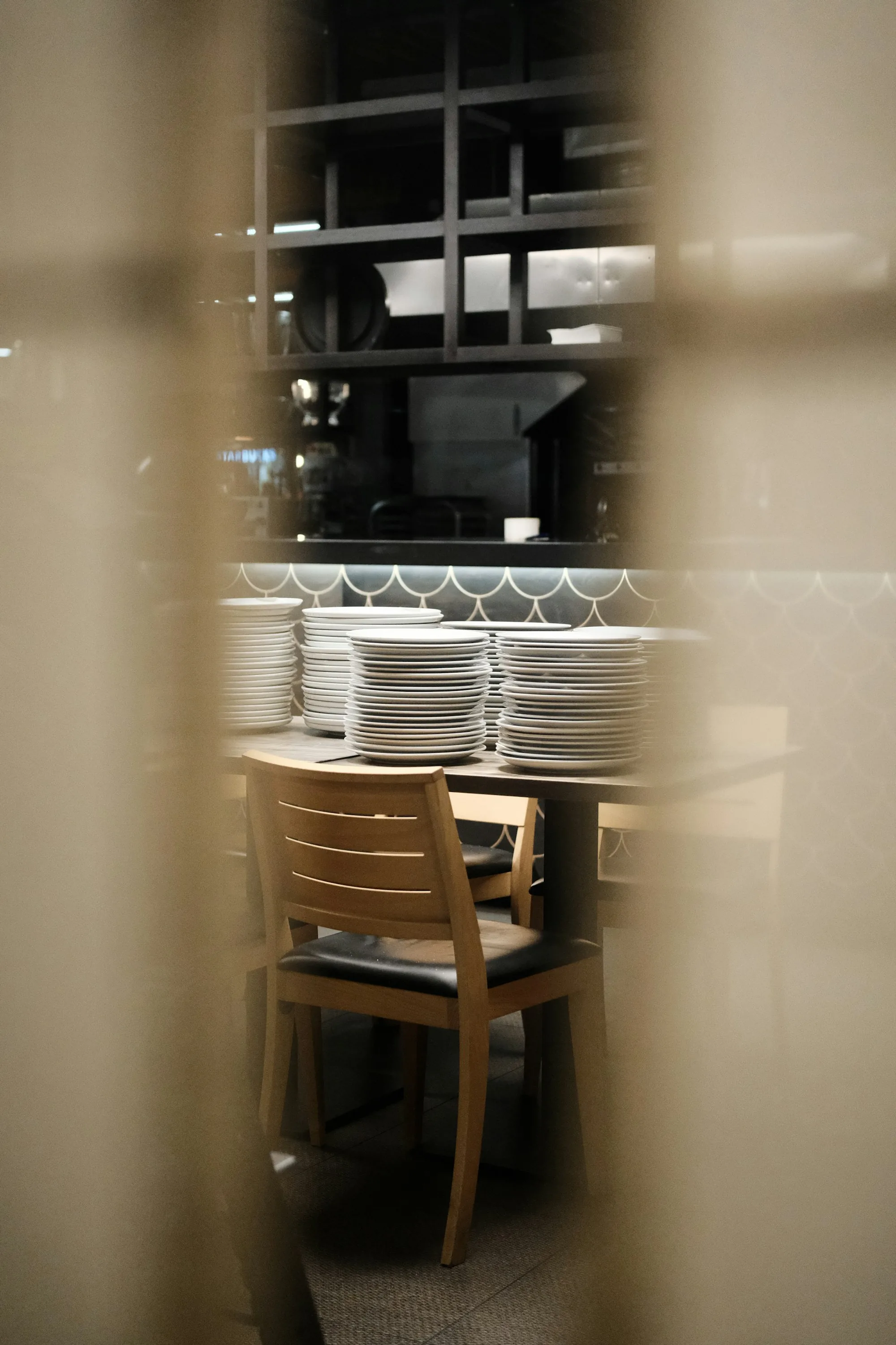 An empty restaurant chair next to stacks of clean plates — the visual metaphor for staff turnover and the work waiting to be done
